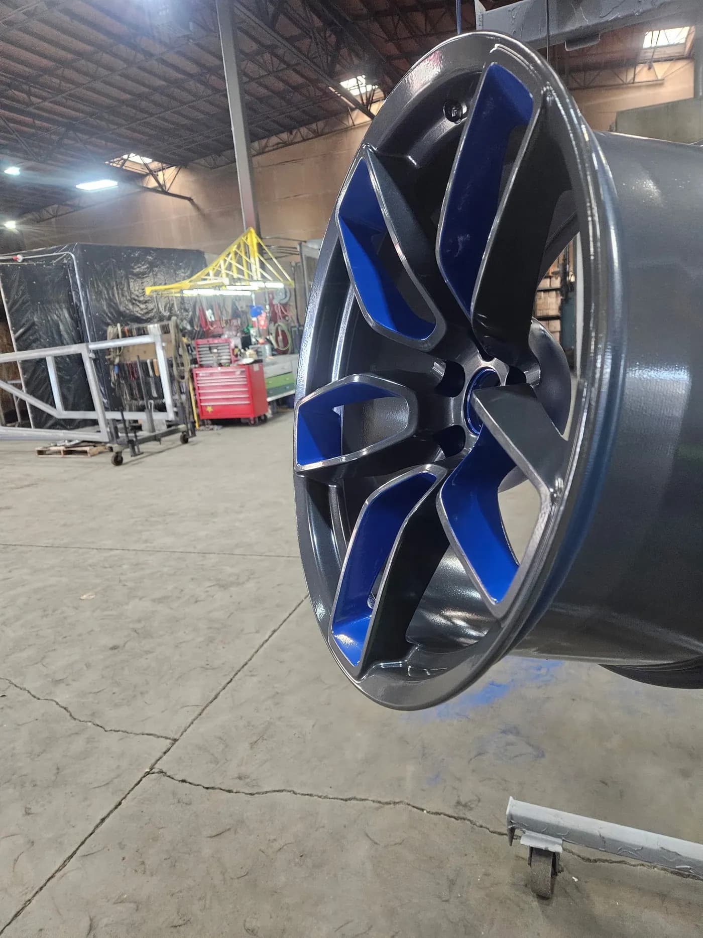 Automotive wheel with glossy blue and black powder coated finish.