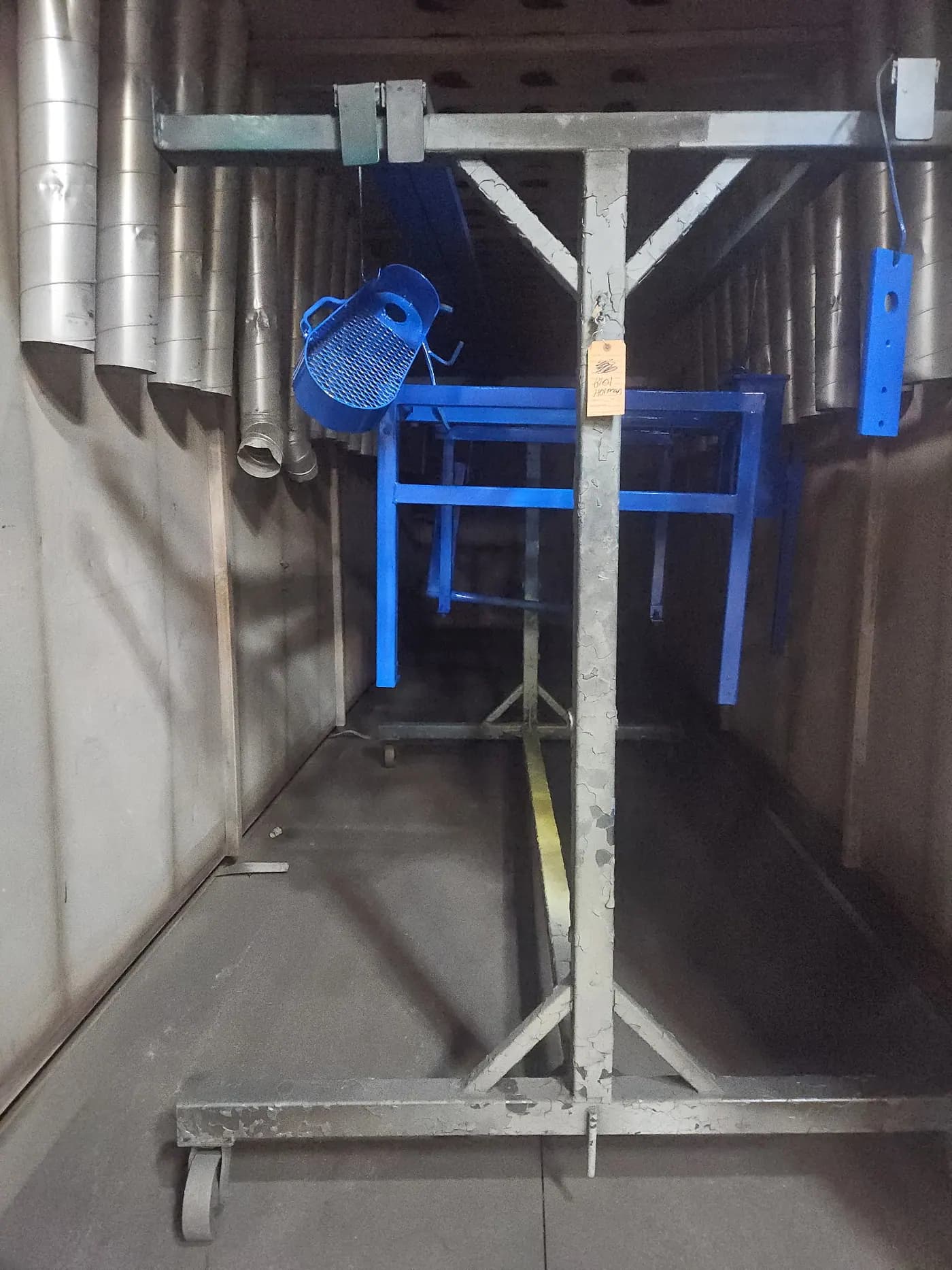 Blue powder coated parts hanging in the shop during finishing work.