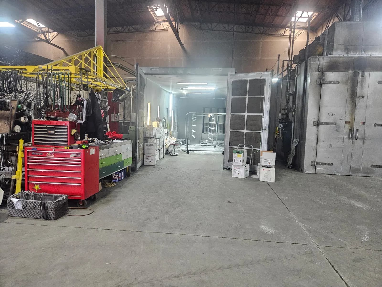 Powder coating equipment and material racks inside the Secoma shop.