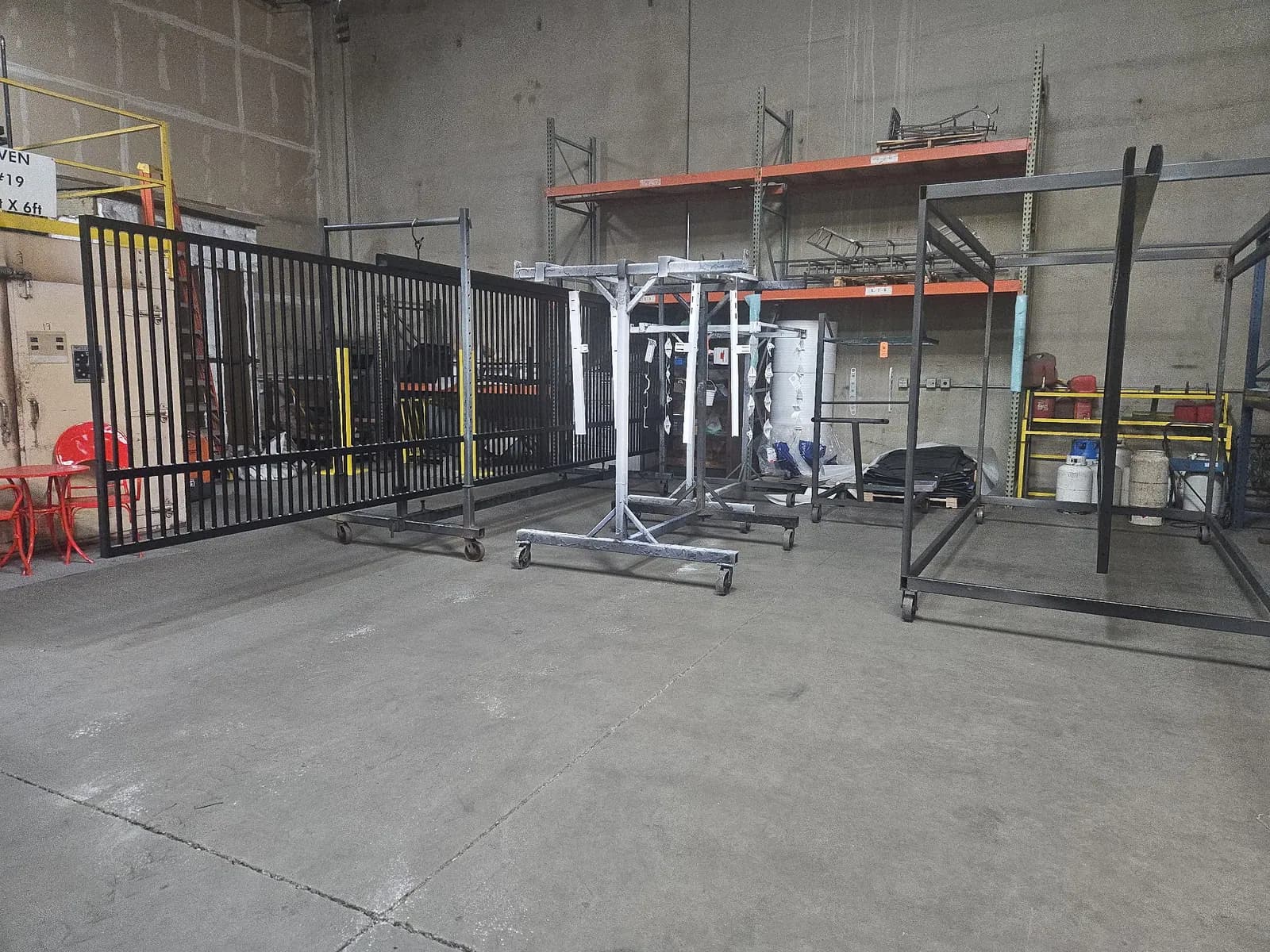 Metal fence and gate sections staged on racks for finishing.