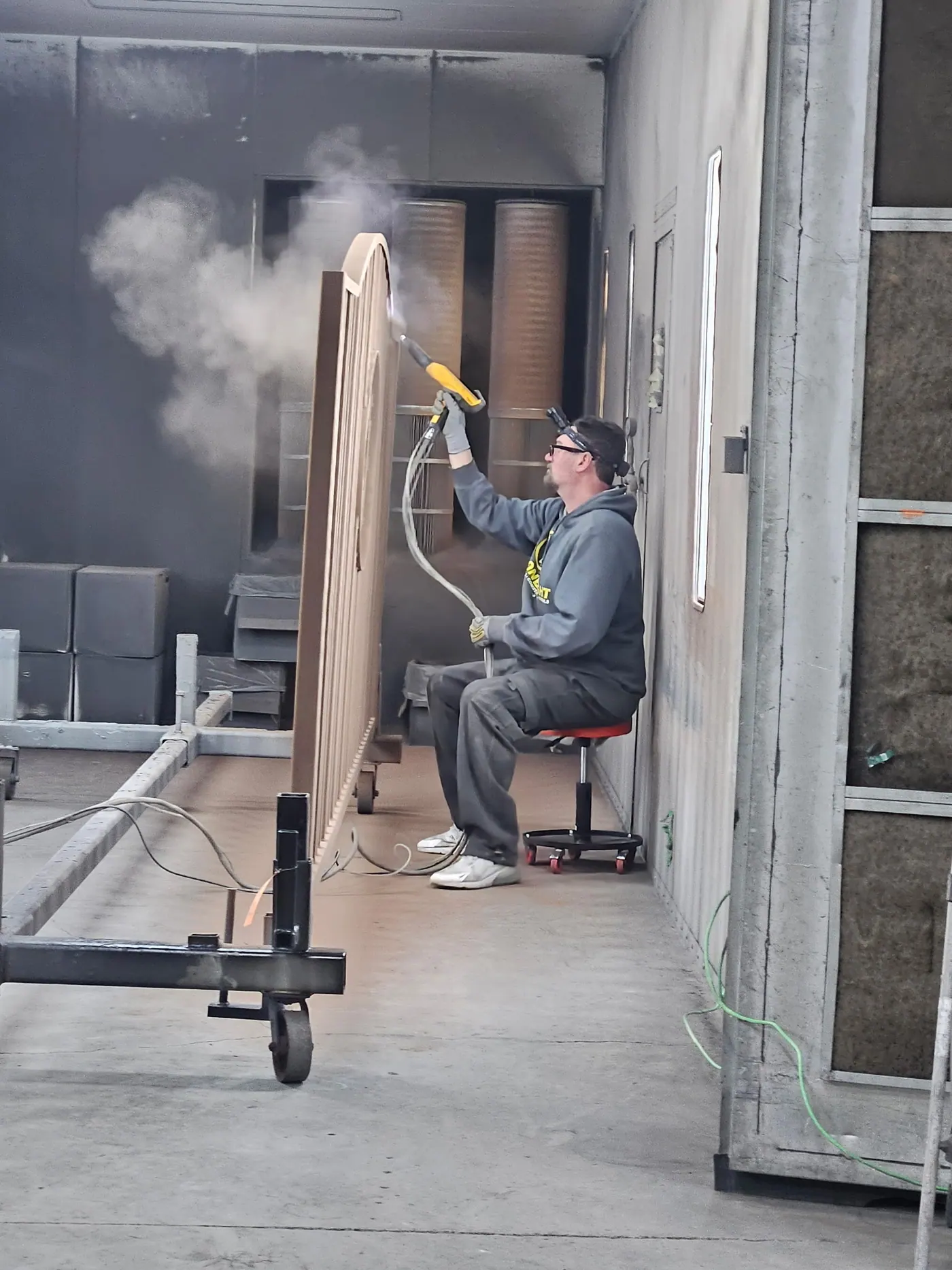 Powder coating being applied inside the spray booth.